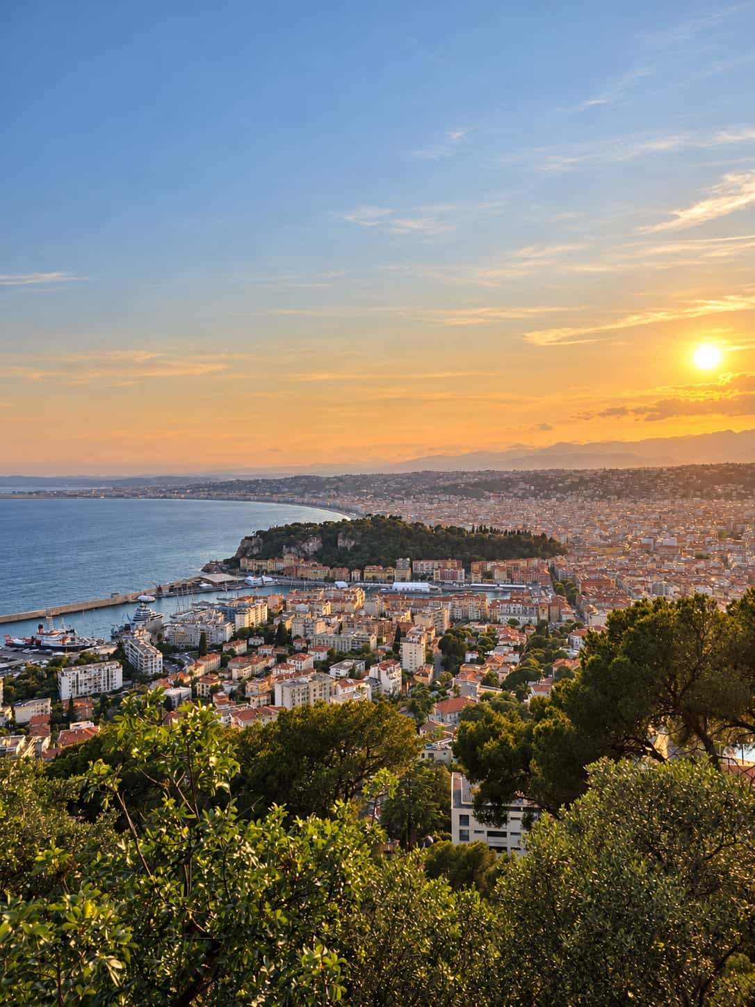 Warm sunset over the Nice port, Castle Hill and curving Baie des Anges, viewed from above