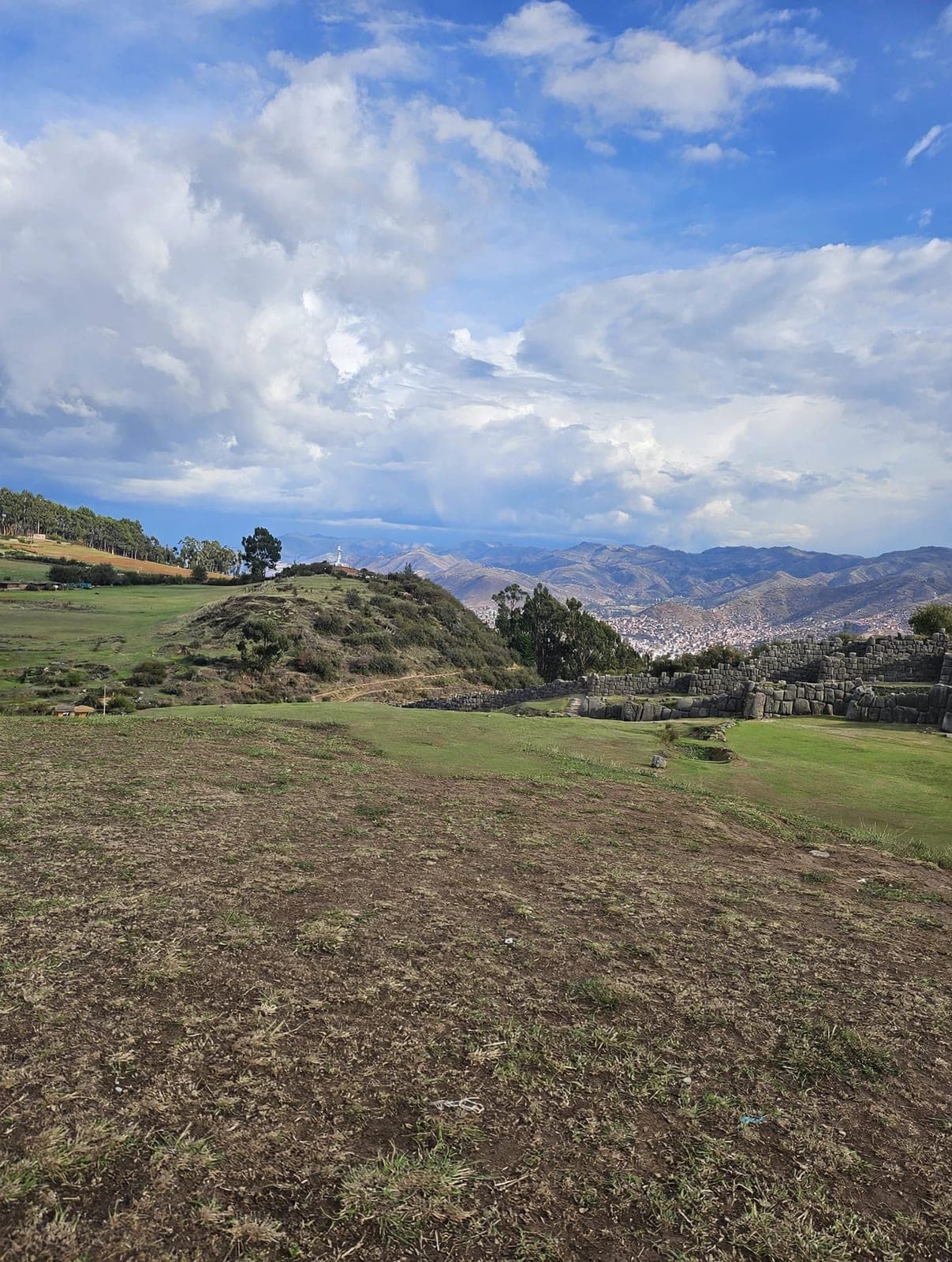 The zigzag stone walls of Sacsayhuamán above Cusco, with the city spread through the valley beyond under a big sky