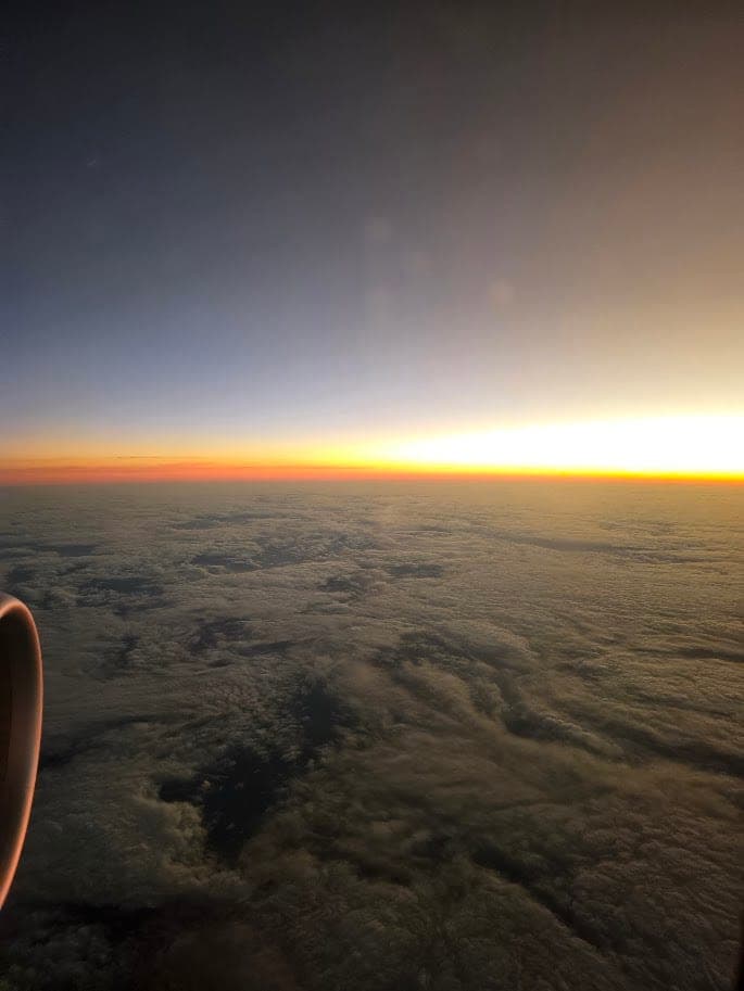 El amanecer visto desde la ventanilla de un avión, sobre una espesa capa de nubes